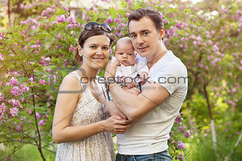 Young couple with newborn son outdoors in spring