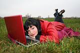 black head woman is laying on a plaid in park grass with notebook