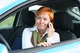Red-haired woman with mobile-phone in a car. She is thinking oups