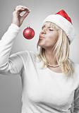 Young blond woman kissing a Christmas ornament