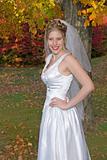 Autumn Bride posing in park near colorful trees.