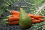 pear on carrots and greens background