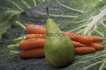 pear on carrots and greens background