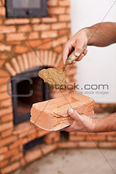 Masonry worker hands with brick and clay mortar on trowel