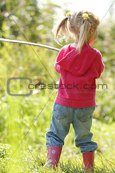 beautiful little girl in nature playing with a stick 