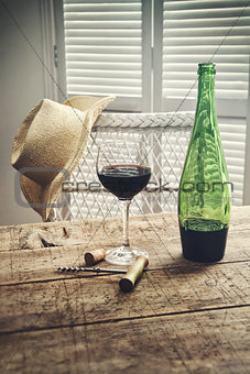 Glass of red wine standing on an old table with straw hat