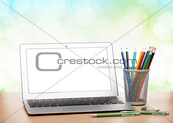 Laptop with blank screen and colorful pencils