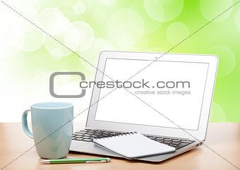Laptop with blank screen and cup on table
