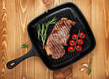 Sirloin steak with rosemary and cherry tomatoes on frying pan