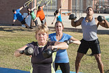 Mature Woman and Group Exercising Outdoors