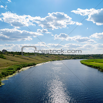 view to river with reflections and blue cloudy sky