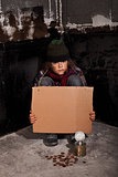 Poor beggar child on the street with blank sign
