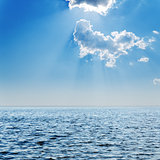blue sea and cloudy sky with sun over it