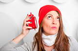 beautiful brunette in a red hat listening alarm clock 