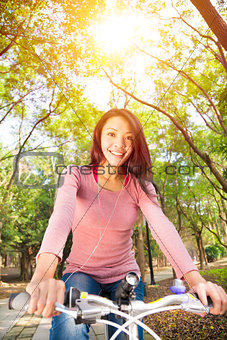 young woman riding bike and listening music on the forest trail