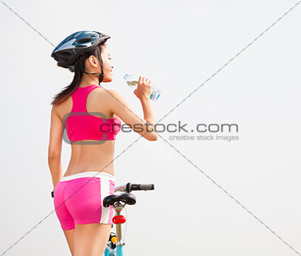 Young woman drinking water and folding bike