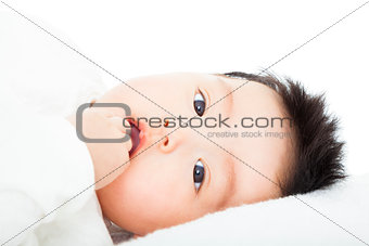 cute baby sucks his thumb lying in bed