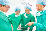 surgeons discussing with tablet in operating theater