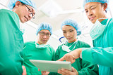 The surgeons useing  tablet  to discuss operating procedure