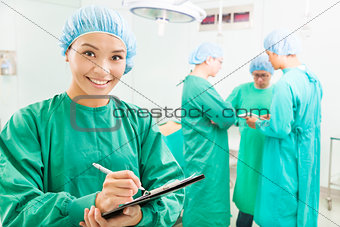 Smiling woman surgeons writing patient operating records