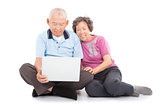 happy senior couple watching or leaning with laptop