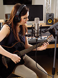 Woman with guitar in a recording studio