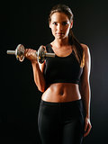 Woman lifting a dumbbell over dark background