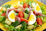 Salad with anchovies on a yellow plate. 