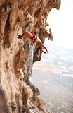 Young female rock climber resting while hanging on rope