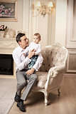 Young man with son sitting in armchair in living room
