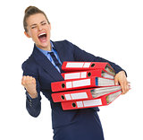 Smiling business woman with stack of documents making fist pump 