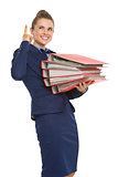 Smiling business woman with stack of folders pointing on copy sp