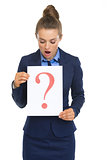 Surprised business woman looking on paper sheet with question ma