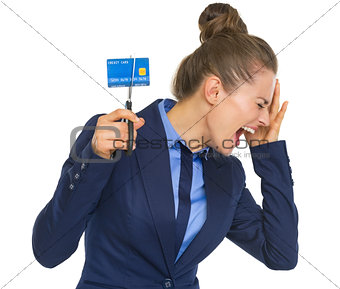 Frustrated business woman cutting credit card