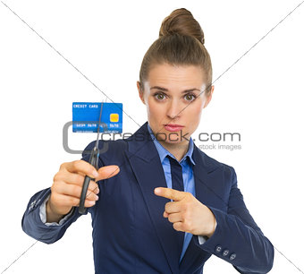 Business woman pointing on credit card squeezed in scissors
