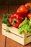 various vegetables in a wooden box (tomatoes, cucumbers, lettuce)