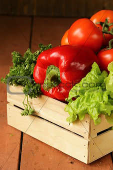 various vegetables in a wooden box (tomatoes, cucumbers, lettuce)