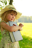 beautiful little girl with the Book in nature