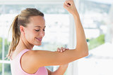 Young woman flexing muscles in the gym