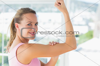 Young woman flexing muscles in gym