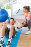 Female trainer looking at young man do abdominal crunches