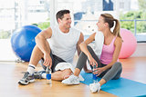 Young couple with water bottles chatting at gym