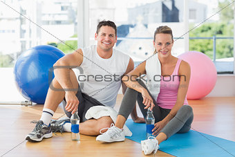 Young couple with water bottles chatting at gym