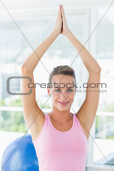 Smiling woman with joined hands over head at fitness studio