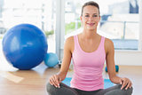 Smiling young woman sitting at fitness studio
