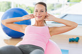 Smiling woman exercising on fitness ball at gym