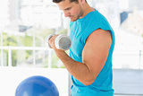 Sporty young man with dumbbell in gym