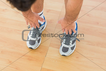 sporty man stretching hands to legs in fitness studio