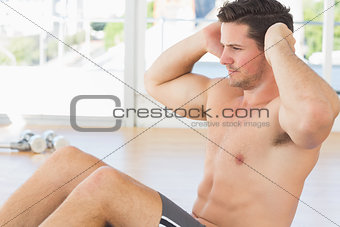 Determined man doing abdominal crunches at gym