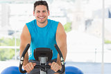 Smiling young man working out at spinning class